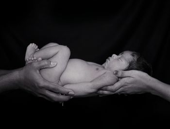 Midsection of couple kissing against black background