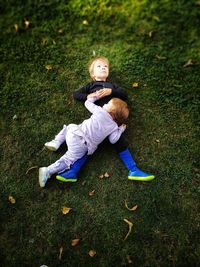 Full length of two little brothers sitting on grassy field