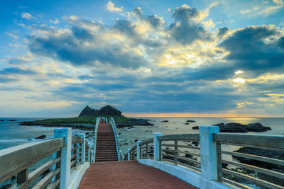 Pier over sea against sky during sunset