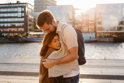 Happy young woman standing against sea in city