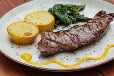 Delicious fried juicy beef on a plate with potatoes and green peppers