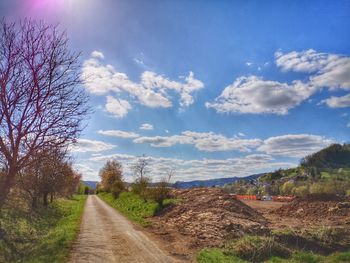 Road amidst field against sky