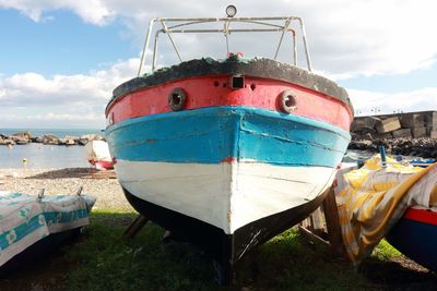 Close-up of boats moored on beach against sky