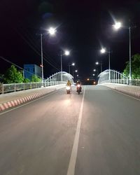 Vehicles on road against illuminated street lights in city at night