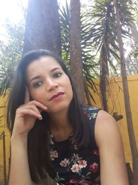 Portrait of young woman against tree