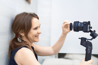 Woman sitting at home recording a blog for video media platforms with mirrorless camera gimball