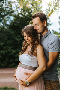 Husband embracing pregnant wife outdoors