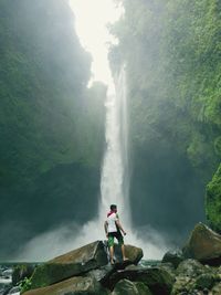 Man standing on the rocks enjoying the waterfall