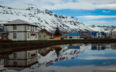 Reflection of houses on snowcapped mountain against sky