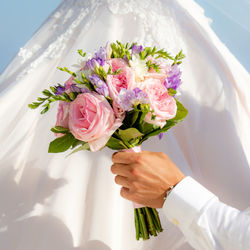 Close-up of hand holding bouquet of white roses