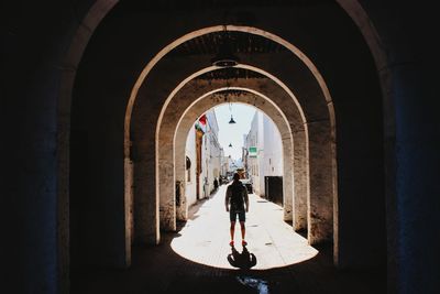 Rear view of man walking on footpath in tunnel