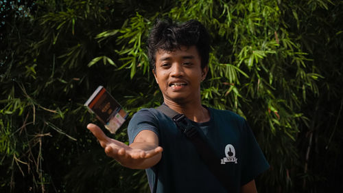 Portrait of young man standing against plants