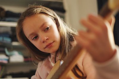 Close-up portrait of girl playing guitar