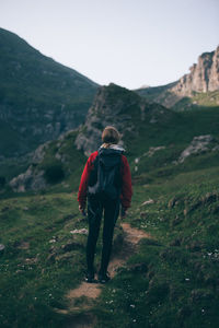 Rear view of woman walking on mountain against clear sky