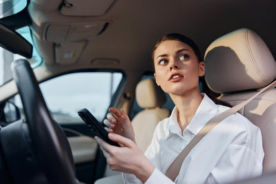 Young woman using mobile phone while sitting in car