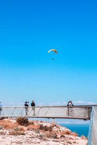 People paragliding against clear blue sky