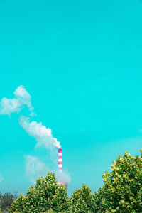 Low angle view of smoke emitting from chimney against blue sky