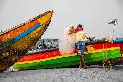 Rear view of men sitting on boat against sea