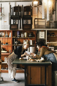 Female coworkers discussing over diary at workbench in upcycling workshop