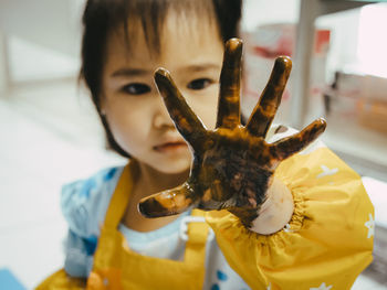 Close-up of baby girl with messy hand sitting at home