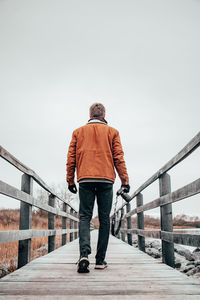 Rear view of man standing on footbridge