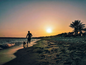 Silhouette people on beach against sky during sunset