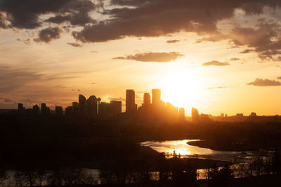 Silhouette buildings in city against sky during sunset