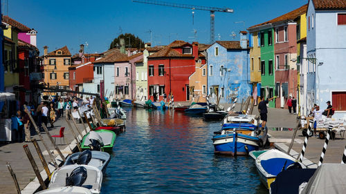 Boats moored in canal amidst buildings in city against sky
