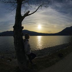 Silhouette boy on beach against sky during sunset