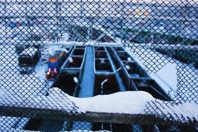 High angle view of trains on snow covered field seen through broken fence