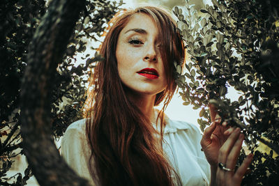 Portrait of beautiful woman standing by plants in park