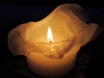 Close-up of lit candle in darkroom