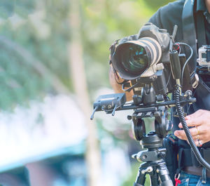 Midsection of man using television camera while standing outdoors