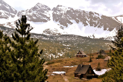 Houses by mountains against sky during winter