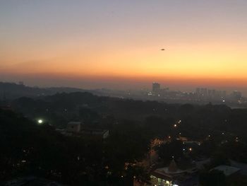 Illuminated cityscape against sky at sunset