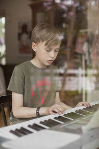 Boy signing while playing piano in house