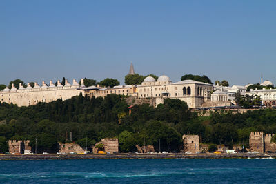 Buildings at waterfront against clear sky