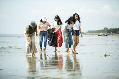 Group of people walking on beach against sky