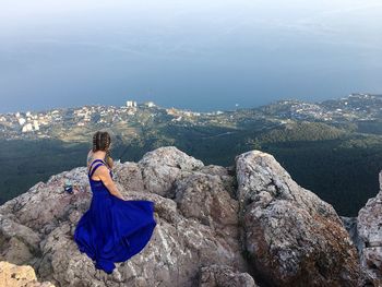 Rear view of woman sitting on rock