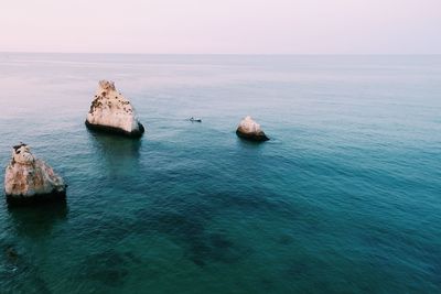 Scenic view of rocks in sea against clear sky