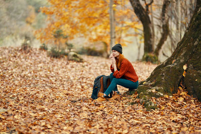 Young woman sitting on leaves during autumn