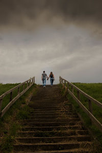 People walking on staircase against sky