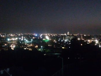 Illuminated cityscape against sky at night