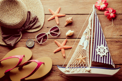 High angle view of personal accessories with navigational compass and boat on wooden table