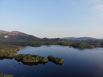 Scenic view of lake and mountains against clear blue sky