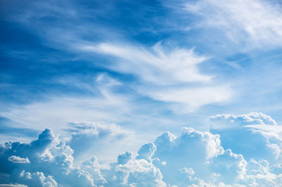 Low angle view of sunlight streaming through clouds