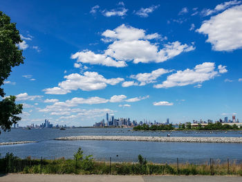 Scenic view of river by buildings against cloudy sky