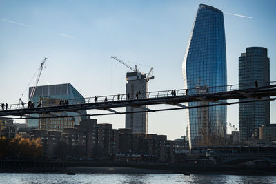 Modern buildings by river against sky in city