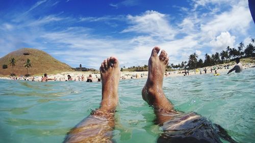 Low section of man on beach against sky