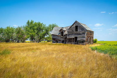 Abandoned house on field against sky